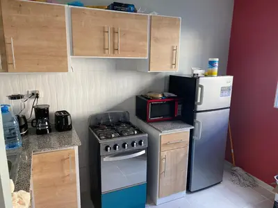 a small kitchen with a stove and a refrigerator at 1st floor 3 Bedrm 2 Baths AC Condo near airport in Los Paredones