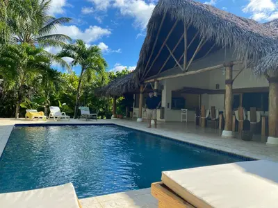 a man standing next to a swimming pool next to a house at Villa de Lima in Las Terrenas