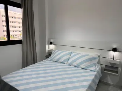 a bed with a striped pillow and a window at Canarock Beach Club in Punta Cana