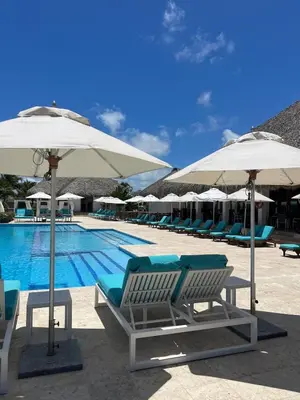 a swimming pool with lounge chairs and umbrellas at Canarock Beach Club in Punta Cana