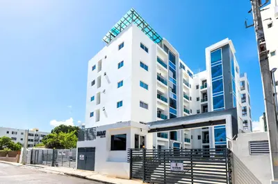 a white apartment building with a fence in front of it at Modern Oasis near Monument with Rooftop BBQ , Gym, and Free Parking in Santiago de los Caballeros