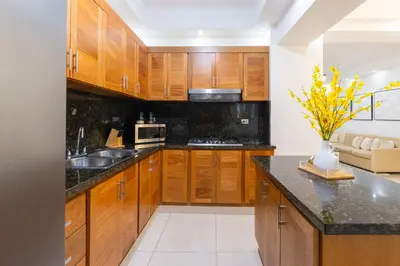 a kitchen with wooden cabinets and a black counter top at Modern Oasis near Monument with Rooftop BBQ , Gym, and Free Parking in Santiago de los Caballeros