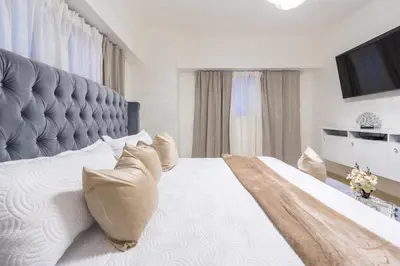 a bedroom with a large white bed with a large headboard at Modern Oasis near Monument with Rooftop BBQ , Gym, and Free Parking in Santiago de los Caballeros