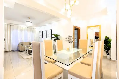a dining room and living room with a glass table and chairs at Modern Oasis near Monument with Rooftop BBQ , Gym, and Free Parking in Santiago de los Caballeros