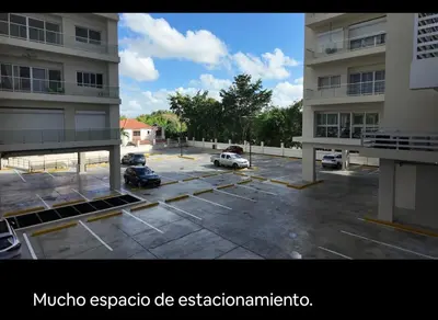 a parking lot with cars parked in front of a building at Ventanas del mar in Los Corrales