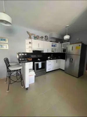 a kitchen with white cabinets and a table and a refrigerator at Cadaqués best sunset in La Fragata