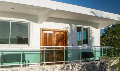 a white house with a pool and two chairs at Villa Rosa Boca Chica in Boca Chica