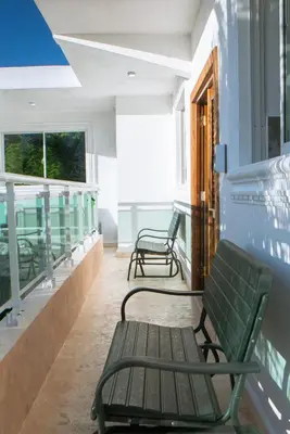 two green benches sitting on the balcony of a building at Villa Rosa Boca Chica in Boca Chica