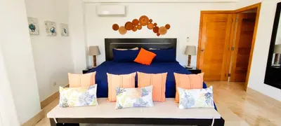 a bedroom with a bed with blue and orange pillows at AMAR'E beach front apartment overlooking pool in Las Terrenas