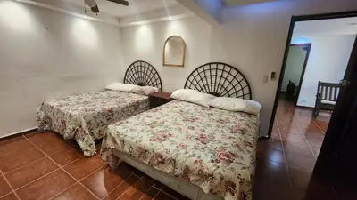 a bedroom with two beds and a mirror at Essential Life La Cuaba Casa de Campo Amenities in Pedro Brand