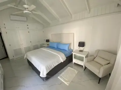 a white bedroom with a bed and a chair at Villa Allegria Los Lagos 57 in La Romana