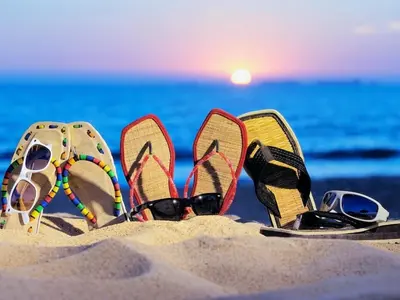 a pair of flip flops and sunglasses in the sand on the beach at Comfort one step away from the beach in Las Terrenas
