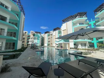 a swimming pool with chairs and tables and buildings at Maple Beach, apartamento en Punta Cana in Punta Cana