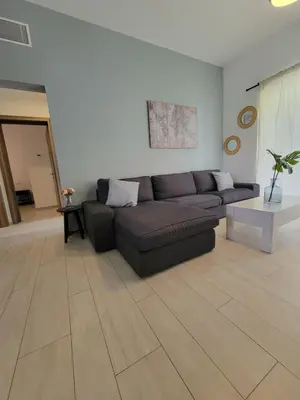 a living room with a couch and a wooden floor at Modern 2BDR - Pool & Golf View in Punta Cana