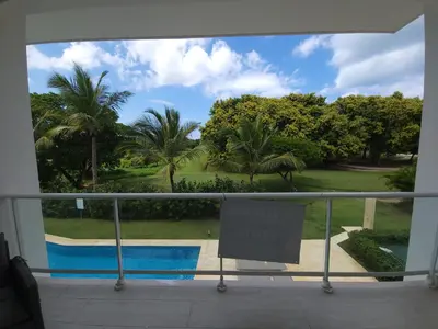 a balcony with a view of a pool and palm trees at Modern 2BDR - Pool & Golf View in Punta Cana