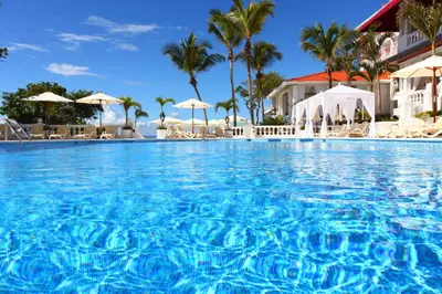 a pool at a resort with palm trees and umbrellas at Bahia Principe Grand Samana - Adults Only in Santa Bárbara de Samaná