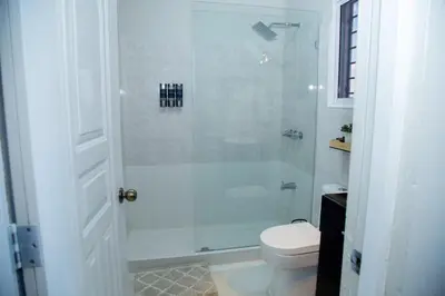 a white bathroom with a shower and a toilet at Luxury 2 bedroom Apartment in Santiago de los Caballeros