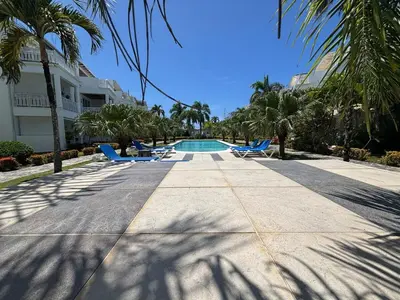 a swimming pool with blue lounge chairs and palm trees at Apartment en residence face à la Mer in Las Terrenas