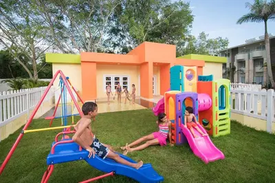 two children playing on playground equipment in front of a house at Emotions by Hodelpa - Juan Dolio in Juan Dolio