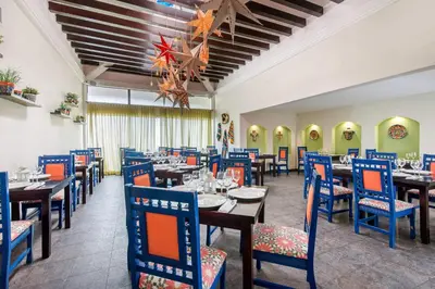 a dining room with tables and blue chairs at Emotions by Hodelpa - Juan Dolio in Juan Dolio