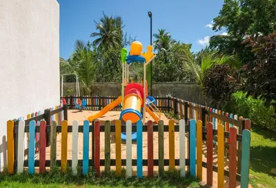 a playground behind a wooden fence with a slide at Upper-Level Penthouse, Beachfront Residence in Las Terrenas