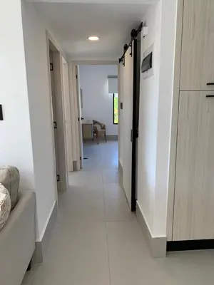 a hallway with white walls and a room with a couch at Prado Suites Luxurious Apartment for Long Term Stay in Las Terrenas