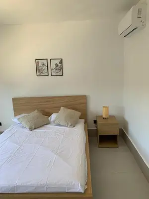 a bedroom with a bed with a nightstand and two pictures on the wall at Prado Suites Luxurious Apartment for Long Term Stay in Las Terrenas