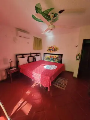 a bedroom with a red bed with a table in it at Hotel El Rancho Sosua in Sosúa