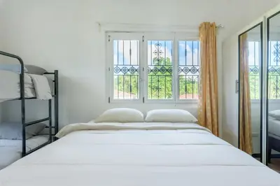 a white bedroom with a bed and two windows at VILLA LEMON Samaná in El Limón
