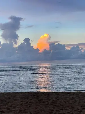 a sunset on the beach with the water and clouds at Waterfront apartment in Las Terrenas