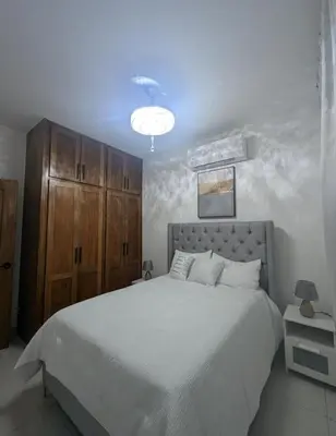 a bedroom with a large white bed with a wooden cabinet at Escapada perfecta, apartamento frente al mar in San Felipe de Puerto Plata