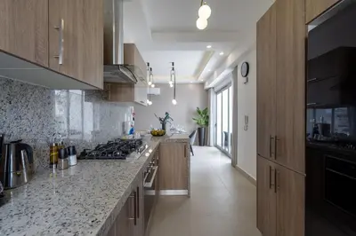 a kitchen with wooden cabinets and a counter top at Splendid-KingBed-3BR-Pool-AC-Modern-WiFi-Yellowkey in Santo Domingo