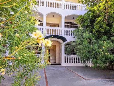 a white house with a white fence and trees at 2-Bedroom Beach Apartment with Pool Costambar in San Felipe de Puerto Plata