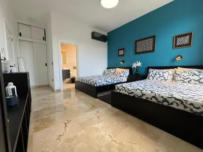 a bedroom with two beds and a blue wall at Golf 218 Playa Nueva Romana in San Pedro de Macorís