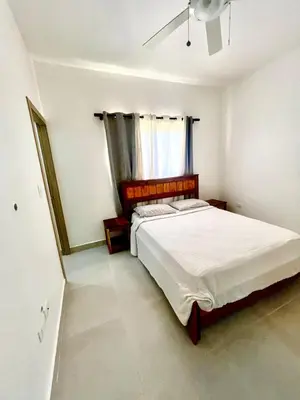 a bedroom with a large white bed with a window at Armonía apartment in Las Terrenas