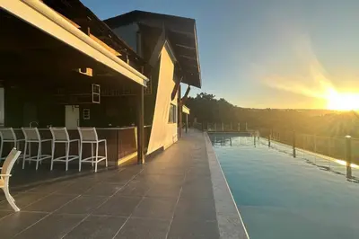 a building with a swimming pool with chairs and the sunset at Peaceful 2BR 2BA in Bonita with Pool and Palm Tree Views in Las Terrenas