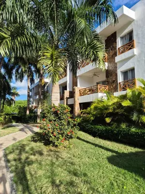 a building with palm trees in front of a yard at Punta Popy 3BR Duplex with Pool, Walk to Beach in Las Terrenas