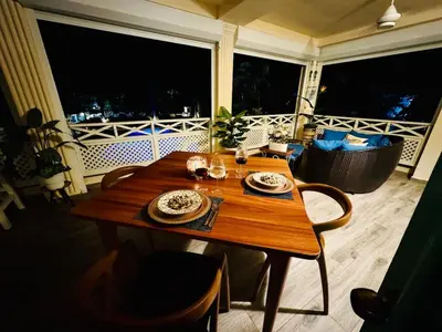 a wooden table with plates and wine glasses on a balcony at Romantic Beachfront Retreat In Las Terrenas - Everything You Could Want - 2 Rooms in Las Terrenas