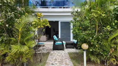 a garden with a chair and trees in front of a house at La Fenice Beachfront Apartment in Las Terrenas