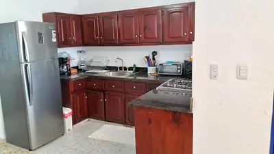 a kitchen with wooden cabinets and a stainless steel refrigerator at CortLang Vacation Rentals, Costambar in San Felipe de Puerto Plata