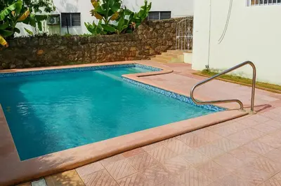 a swimming pool with a metal rail next to a house at CortLang Vacation Rentals, Costambar in San Felipe de Puerto Plata
