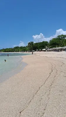 a sandy beach with people in the water at CortLang Vacation Rentals, Costambar in San Felipe de Puerto Plata