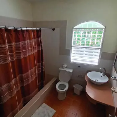 a bathroom with a toilet and a sink and a window at El jardín del coco in Las Galeras