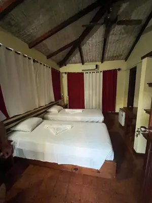 two beds in a room with red and white curtains at Hotel palococo in Las Terrenas