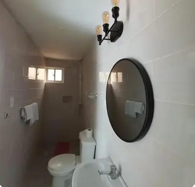 a bathroom with a white toilet and a mirror at Hospedaje Las Flores Pedernales in Pedernales