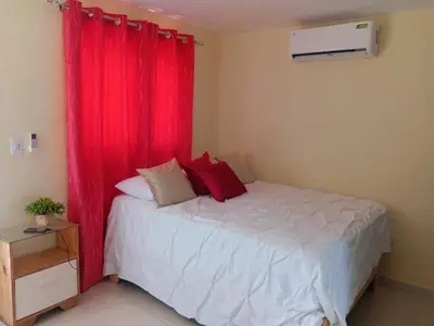 a bedroom with a bed with a red curtain at Hospedaje Las Flores in Pedernales