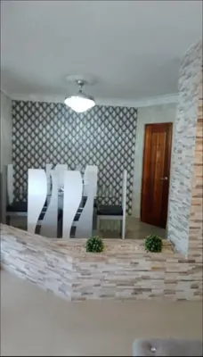 a dining room with white chairs and a brick wall at Hermoso apartamento 3 habitaciones in Los Paredones