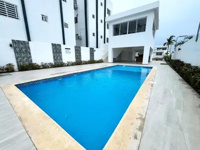 a swimming pool in front of a building at Family-friendly apartment near the beach in Boca Chica