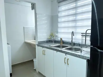 a white kitchen with a sink and a window at Family-friendly apartment near the beach in Boca Chica