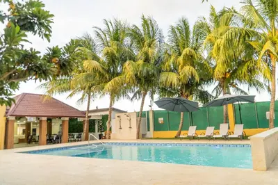 a pool with palm trees and chairs and umbrellas at Terrenal Paradise in Esperanza